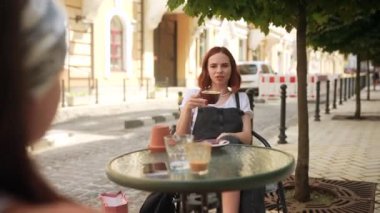 İletişim ve arkadaşlık kavramı. Kafede kahve fincanlarıyla gülümseyen genç kadınlar.