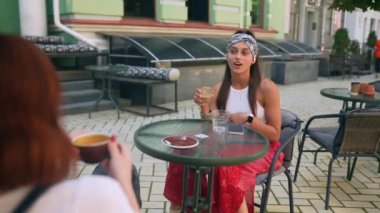 İletişim ve arkadaşlık kavramı. Kafede kahve fincanlarıyla gülümseyen genç kadınlar.