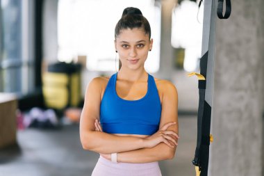 Spor salonunda kameraya poz veren güzel bir genç kadın. Şehvetli genç kadın, kameraya bak.