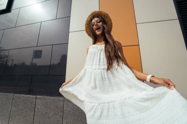 Güzel bir mizah anlayışı olan sevimli genç bir kadın. Şehir sokağında kameraya gülüyor.