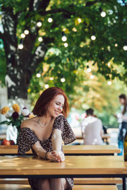 Arka plandaki yazlık kafede terasta kahve içen iki kız arkadaşın yakın plan portresi.