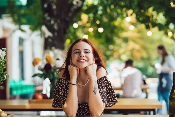 Arka plandaki yazlık kafede terasta kahve içen iki kız arkadaşın yakın plan portresi.