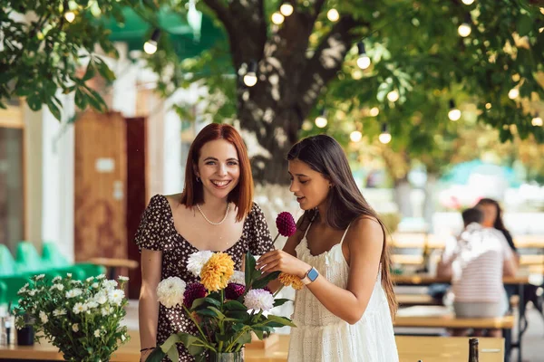 2人の若い女性が注文を取り 美しいお祝いの花束を作ります 花屋さんやストリートカフェで花束を作る 中小企業 — ストック写真