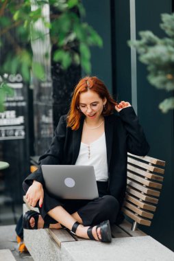 Laptopta çalışan, kafede oturup kahve içen çekici bir kadının fotoğrafı.