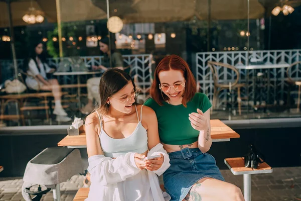 Duas Jovens Excitadas Usando Telefones Celulares Enquanto Sentam Café Livre — Fotografia de Stock