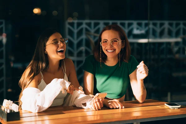 Duas Jovens Excitadas Usando Telefones Celulares Enquanto Sentam Café Livre — Fotografia de Stock