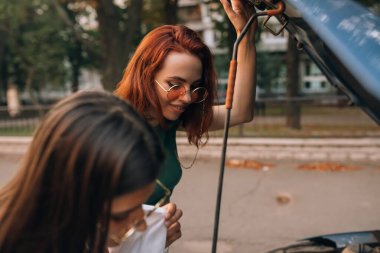 Arabası bozulmuş kadınlar yolda. Yardım edecek birini bul..