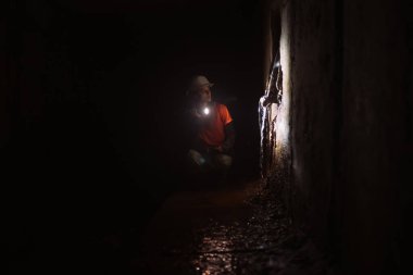 Elinde fener olan genç bir kadın kazıcı tüneli keşfediyor.