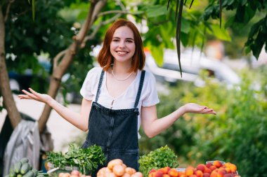 Kadın satıcı tezgahta sebzelerle.