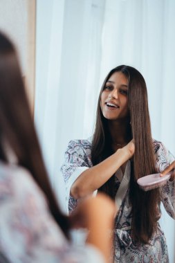 Aynanın önünde saçını tarayan bir kadın..