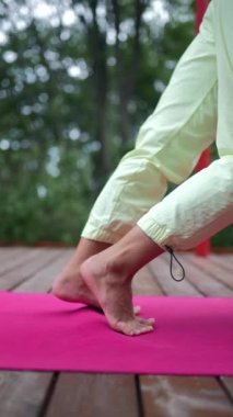 Genç bir kadın sabah tahta bir podyumda yoga yapıyor.