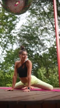 Genç bir kadın sabah tahta bir podyumda yoga yapıyor.