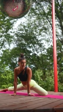 Genç bir kadın sabah tahta bir podyumda yoga yapıyor.