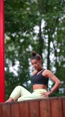 Genç bir kadın sabah tahta bir podyumda yoga yapıyor.