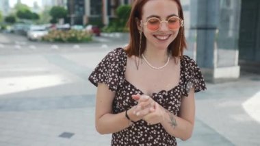 Genç ve güzel bir kız sokakta kameraya konuşuyor.