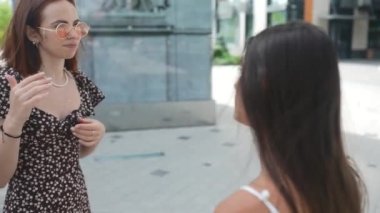 Genç kadınlar şehir sokaklarında konuşuyor ve gülüyor.