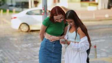 İki turist arkadaş akıllı bir telefondan online rehbere başvuruyor.