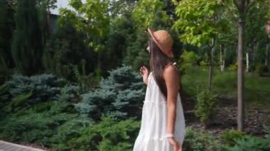 Genç, güzel, esmer bir kadın. Sokakta yürüyor, yaz seti açık.