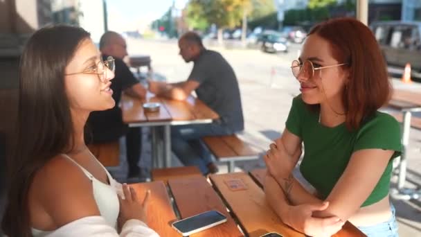 Две Симпатичные Девушки Разговаривают Сидя Баре Городской Улице — стоковое видео