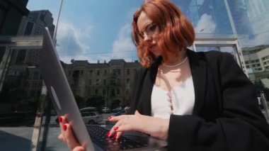 Gülümseyen kadın dışarıda dizüstü bilgisayarına bakıyor, modern yaşam tarzı, bağlantı, iş, kahve molası, iletişim, web sohbeti, sosyal medya, video konferans konsepti.