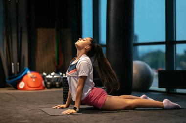 Egzersiz yapan, yoga yapan veya spor salonunda pilates yapan genç bir kadın.