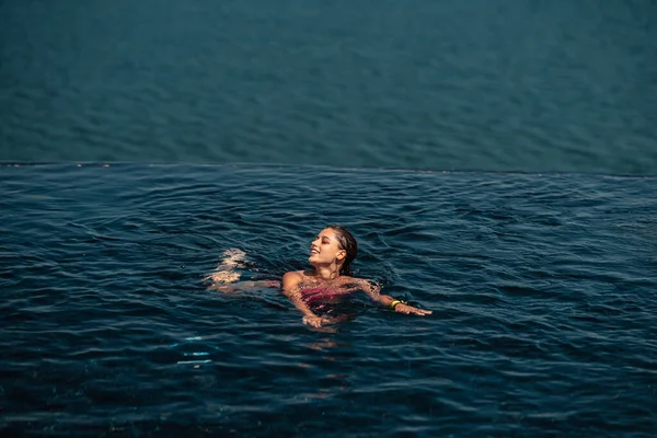 Счастливая Женщина Купальнике Плавает Бесконечном Бассейне Роскошном Отеле Фоне Моря — стоковое фото