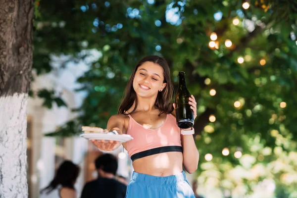 Young Woman Carries Plate Snacks One Hand Drink Other — 图库照片