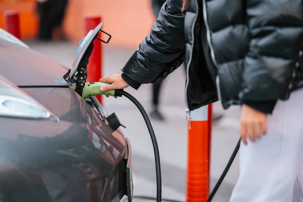 Молодая Красивая Женщина Путешествует Электрическом Автомобиле Останавливаясь Зарядной Станции Стоя — стоковое фото