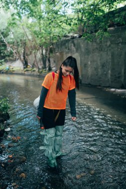 Genç bir kadın kazıcı bir yağmur toplayıcısının yanında yürüyor.