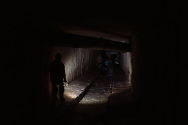 Elinde fener olan genç bir kadın kazıcı tüneli keşfediyor.