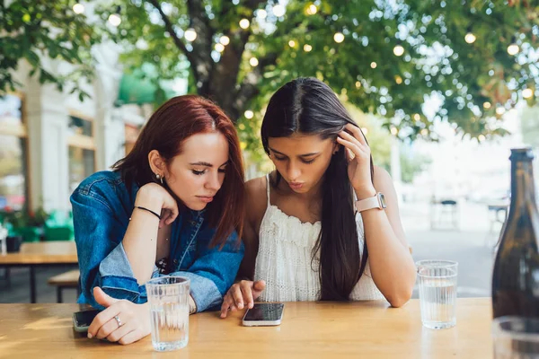 Duas Amigas Navegando Telefones Celulares Enquanto Sentadas Juntas Café Rua — Fotografia de Stock