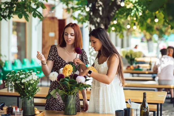 2人の若い女性が注文を取り 美しいお祝いの花束を作ります 花屋さんやストリートカフェで花束を作る 中小企業 — ストック写真