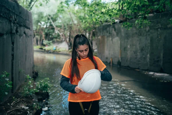 一个年轻的女挖掘机沿着一个雨水收集器走着 — 图库照片