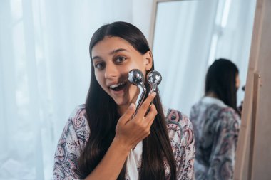 Çekici bir kadın, Y şeklinde top silindiriyle yanağına masaj yapıyor. Güzellik ve cilt bakımı