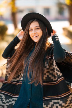 Pançolu ve şapkalı şık bir kadın sonbahar doğasını seviyor. İnsanlar, özgürlük, yaşam tarzı, seyahat ve tatil kavramı.