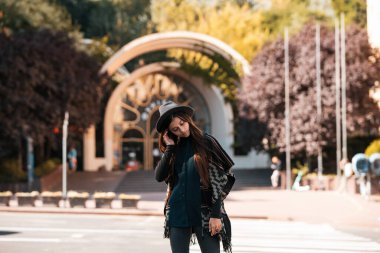 Şehir caddesinde şapkalı ve pançolu güzel moda bir kadın.