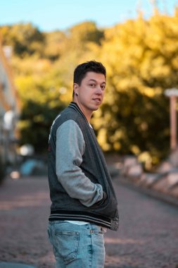 Sokakta yürüyen ve kameraya bakarak ciddi genç adam resmi.