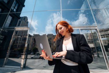 Gülümseyen kadın dışarıda dizüstü bilgisayarına bakıyor, modern yaşam tarzı, bağlantı, iş, kahve molası, iletişim, web sohbeti, sosyal medya, video konferans konsepti.