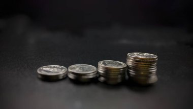 merdiven konseptinde siyah arkaplan üzerine gümüş paralar istiflenmiş finansal iş büyümesi