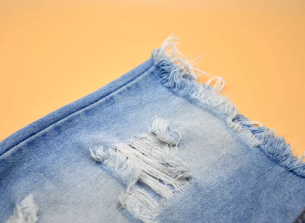 Jeans Azzurri Hanno Strappi Uno Sfondo Arancione Popolare Concetto Moda — Foto Stock