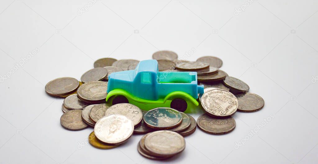A blue-green pickup truck surrounded by piles of coins on a white background.