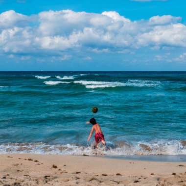 Küba 'da bir sahilde hindistan ceviziyle oynayan bir çocuk.