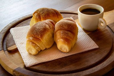 Kesme tahtasında üç ev yapımı çörek ve bir fincan sade kahve. Kahvaltı..