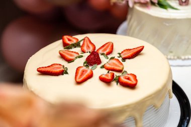  Bir doğum günü partisi için dekore edilmiş bir masanın üzerine krema ve çilekle süslenmiş pasta..