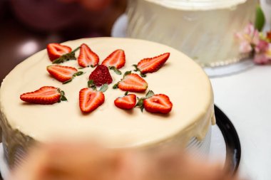  Bir doğum günü partisi için dekore edilmiş bir masanın üzerine krema ve çilekle süslenmiş pasta..
