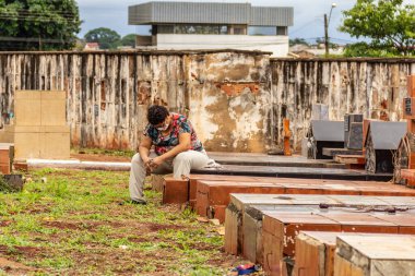 Mezarda oturan üzgün bir insan. Tüm Ruhlar Günü.