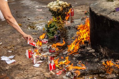 Bir mezarlıkta mum yakan birinin kolu. Tüm Ruhlar Günü.