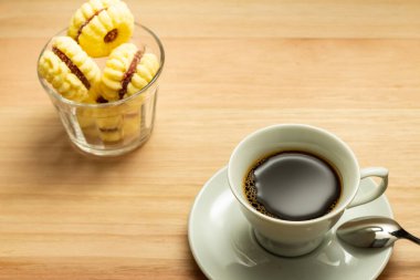  Tahta bir yüzeye şeker serpiştirilmiş bir fincan tereyağlı kurabiye..