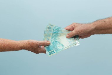 Yaşlı bir adamın başka birine ödeme yapması. Birbirine para veren iki yaşlı insanın elleri. Para ödemek ve almak. Ödeme kavramı.