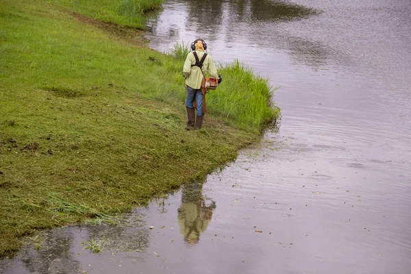 Uygun Ekipmanlarla Gölün Kenarında Çim Biçen Bir Işçi — Stok fotoğraf
